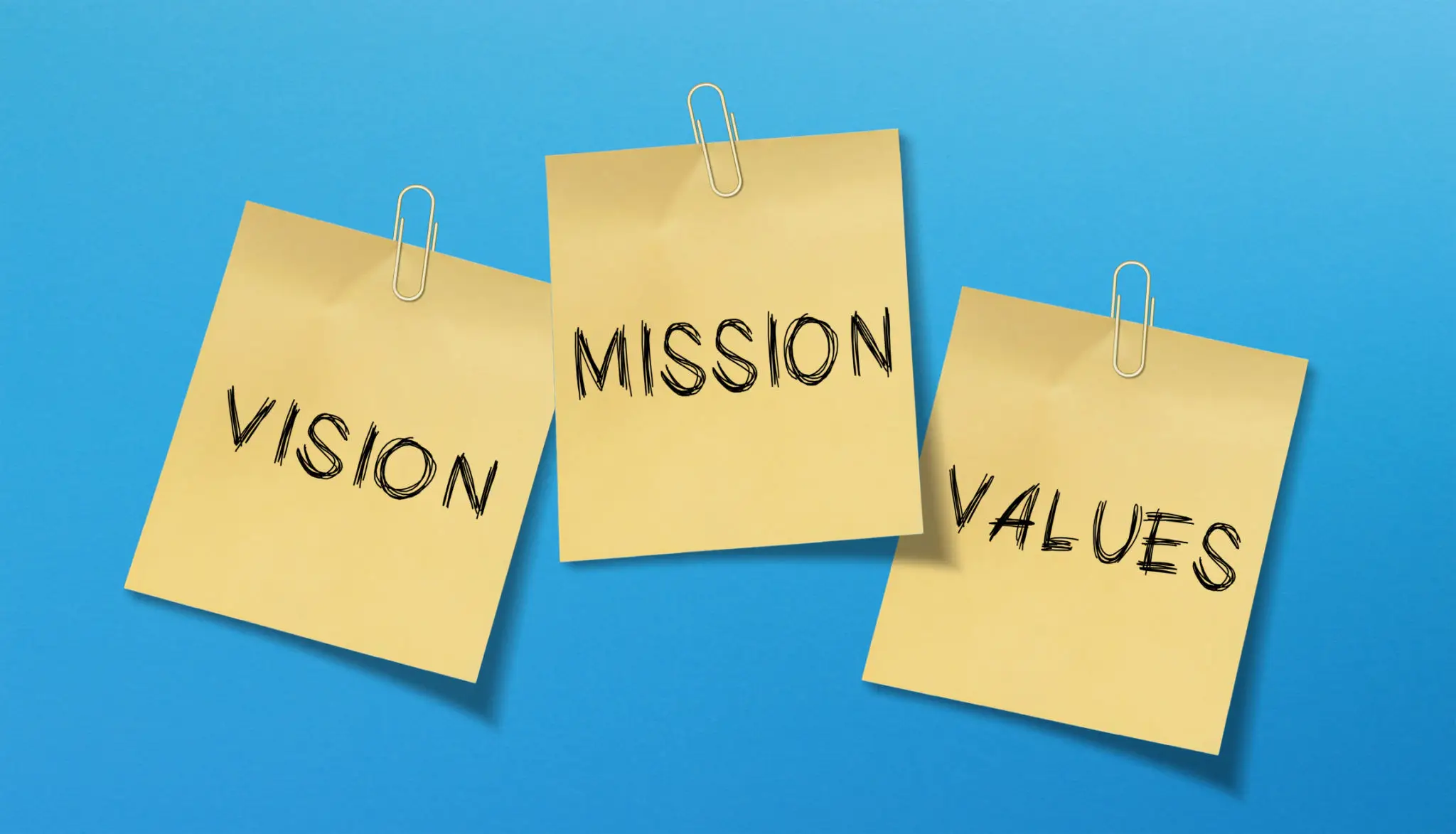 Sticky notes with the words Mission, Vision, and Values against a blue background.