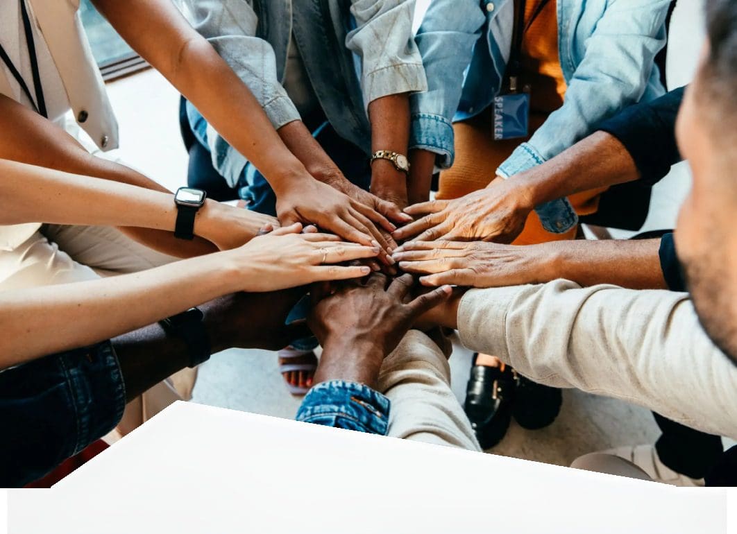 Diverse group joining hands in teamwork gesture.