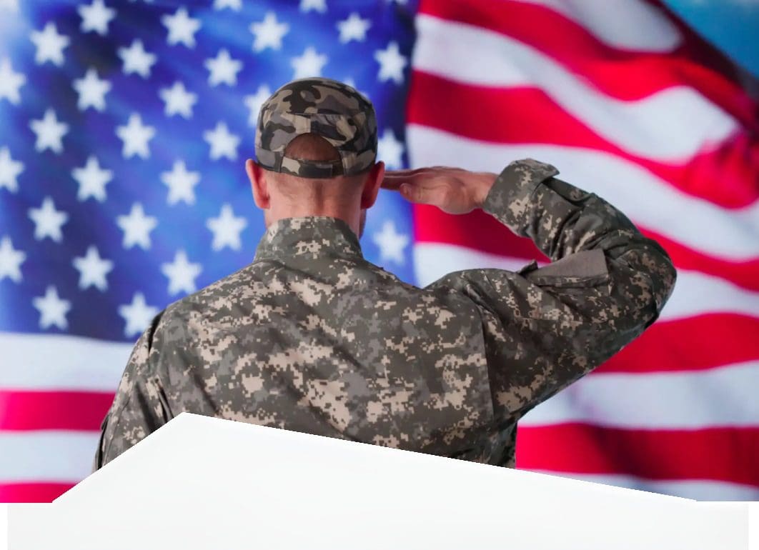 Soldier in camouflage saluting before an American flag.