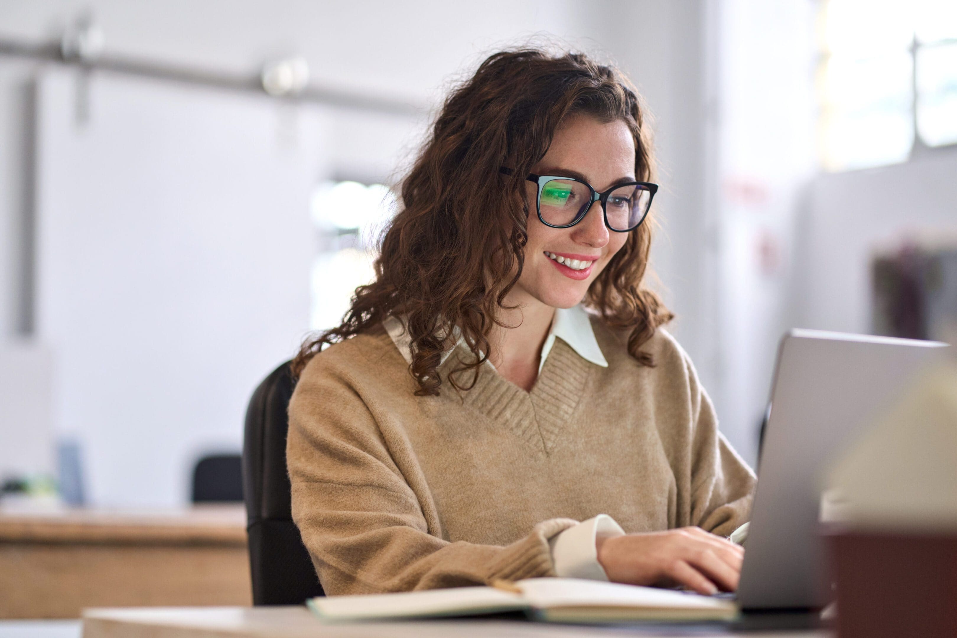 Woman smiling while working on a laptop.
