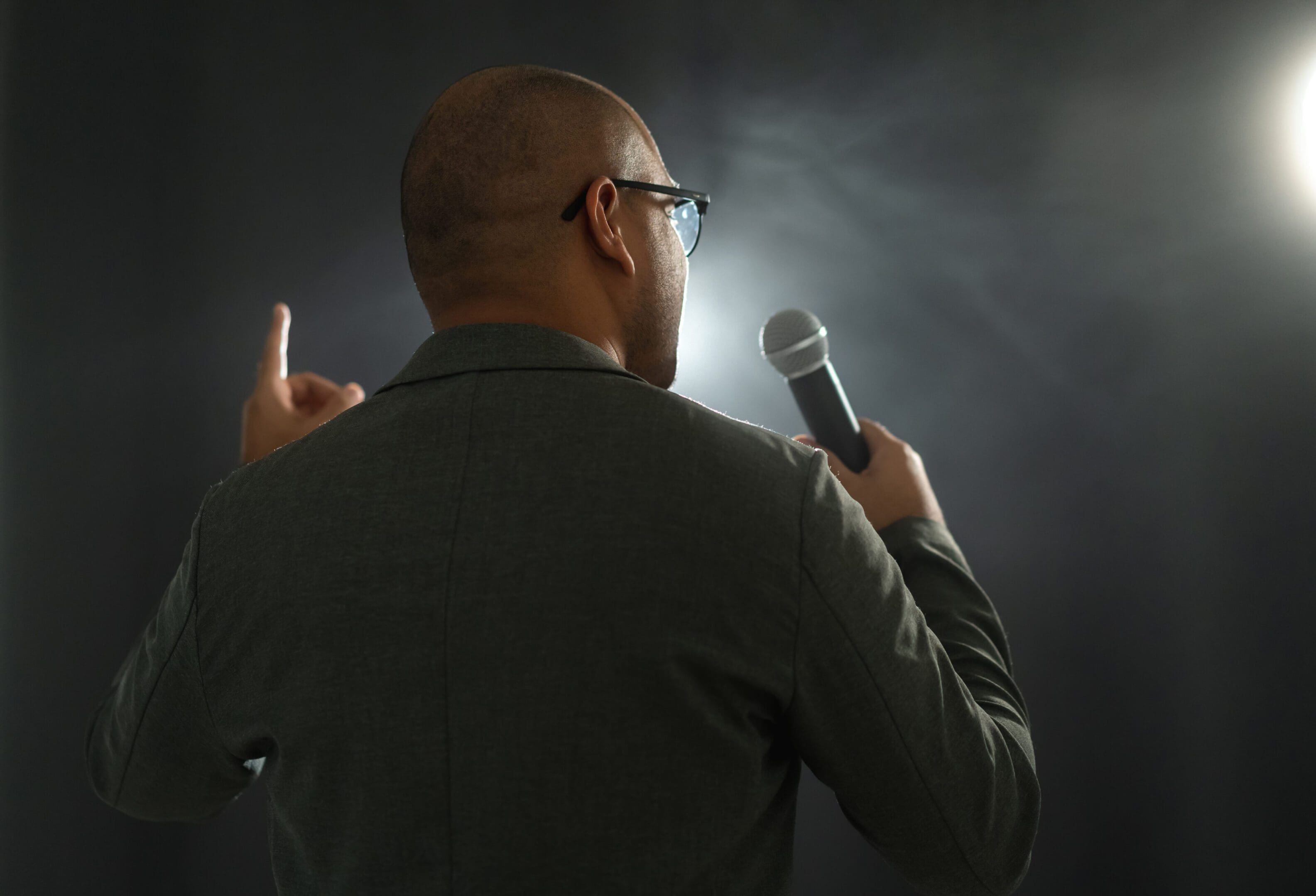 Man speaking on stage with microphone.