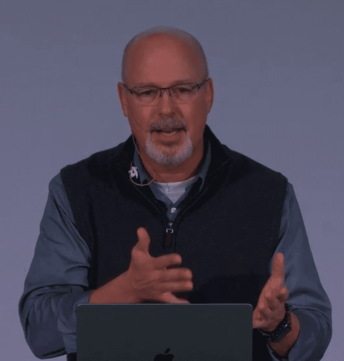 Man speaking with hand gestures in a professional setting.
