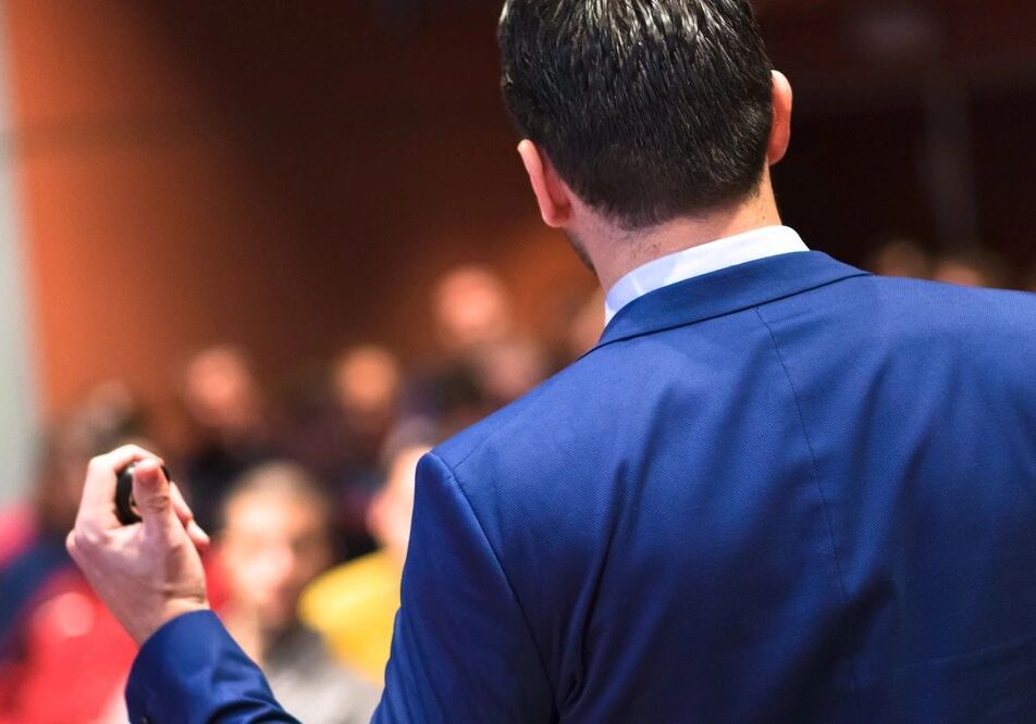 Speaker presenting to an audience in auditorium.